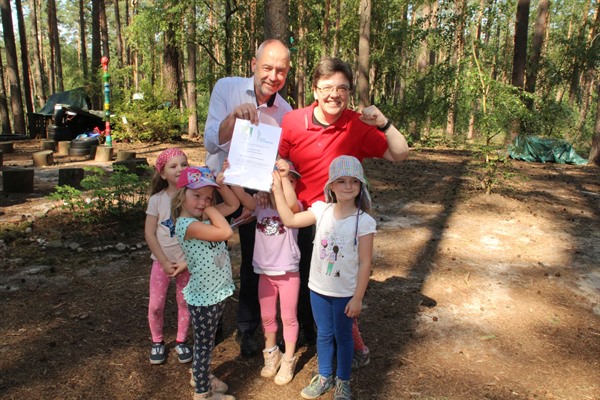 DRK-Waldkindergartenleiterin Jasmin Waltje und einige der Kinder nehmen die Urkunde von Bürgermeister Martin Feller entgegen. 
