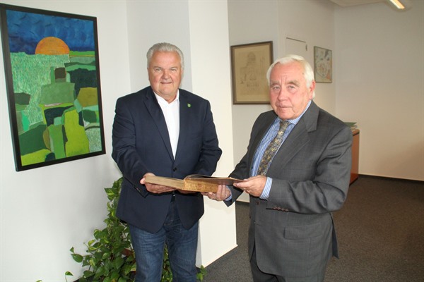 Stadtdirektor Hans-Jürgen Kammer (links) nimmt das Buch „Deutsches Badewesen in vergangenen Tagen“ von Hans-Bernd Kaufmann entgegen. 