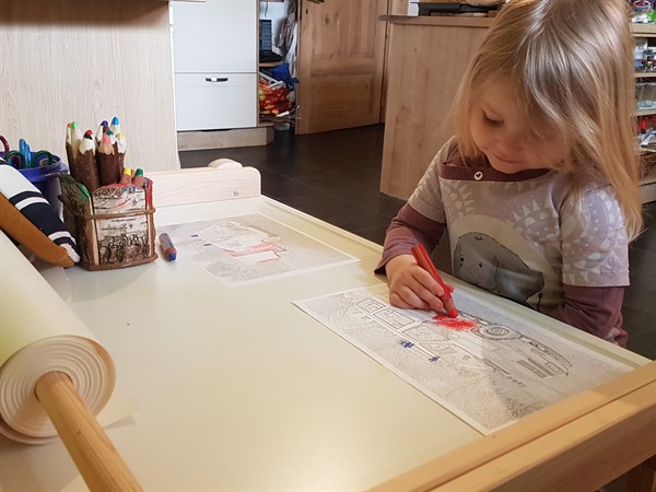 Die dreijährige Leni malt eine Vorlage der Feuerwehr-Fahrzeuge aus.
